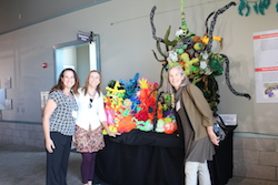 three attendees stand in front of a crochet coral reef